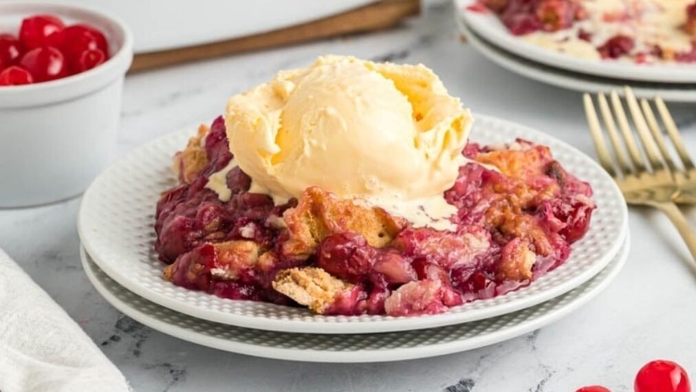 Cherry dump cake on a white plate with a fork.