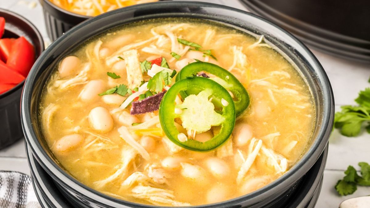 White chicken chili in a black bowl with peppers.
