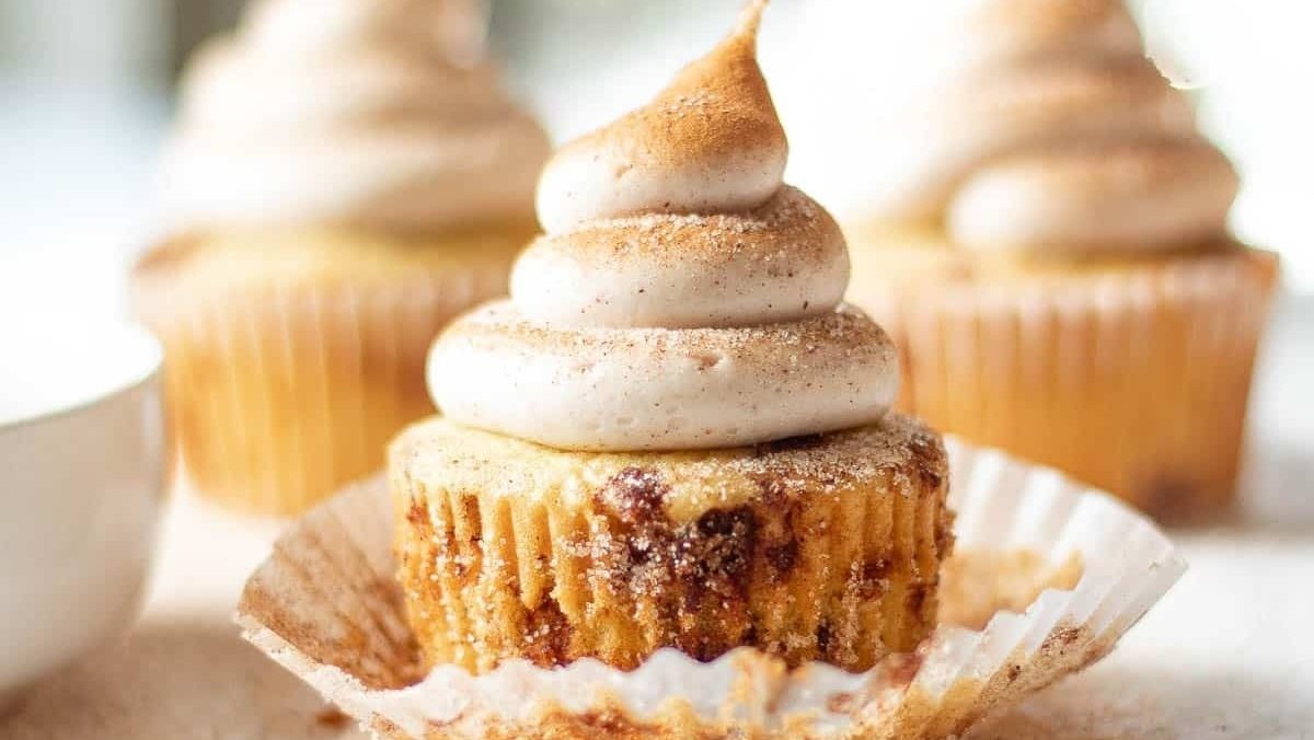 Christmas-themed cupcakes topped with whipped cream and a cup of coffee.