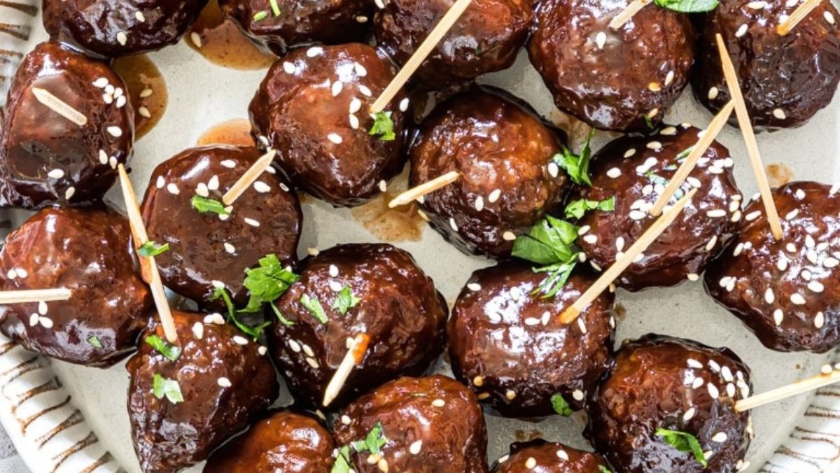Glazed meatballs on a plate with toothpicks.