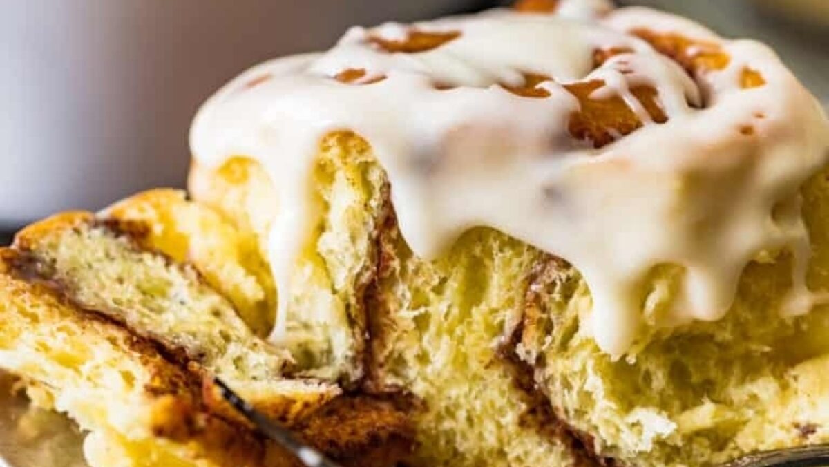 Cinnamon rolls adorned with sweet icing are perfectly arranged on a plate.