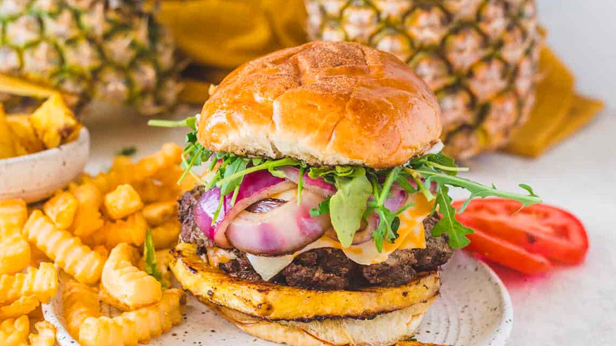 A pineapple burger on a plate with fries.