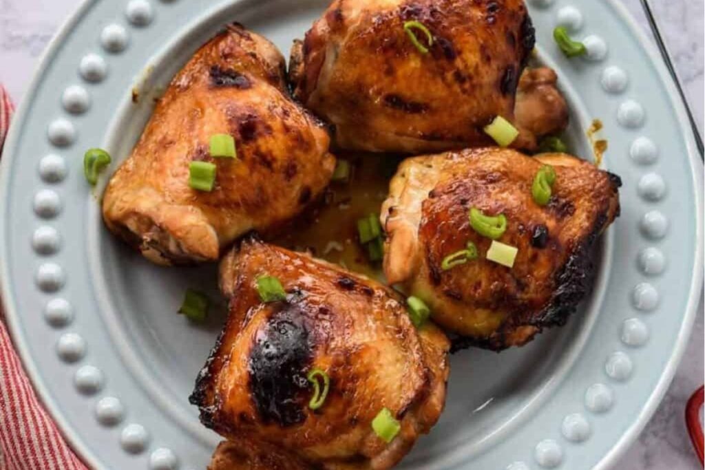 Pieces of soy glazed chicken thighs served on a plate.