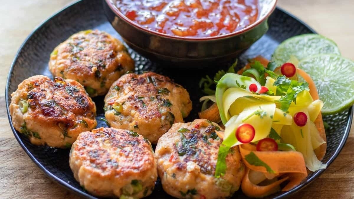 Asian-inspired Thai chicken burgers with dipping sauce on a plate.