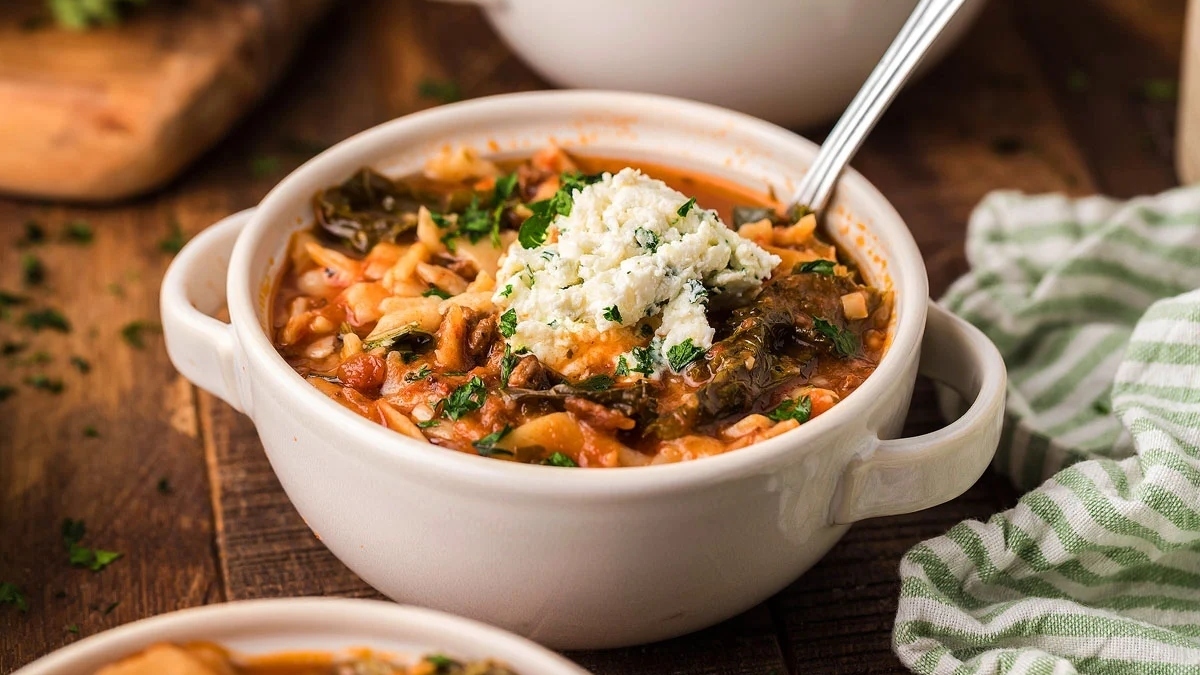 A comforting bowl of soup, perfect for chilly winter dinners, placed on a rustic wooden table with a spoon.