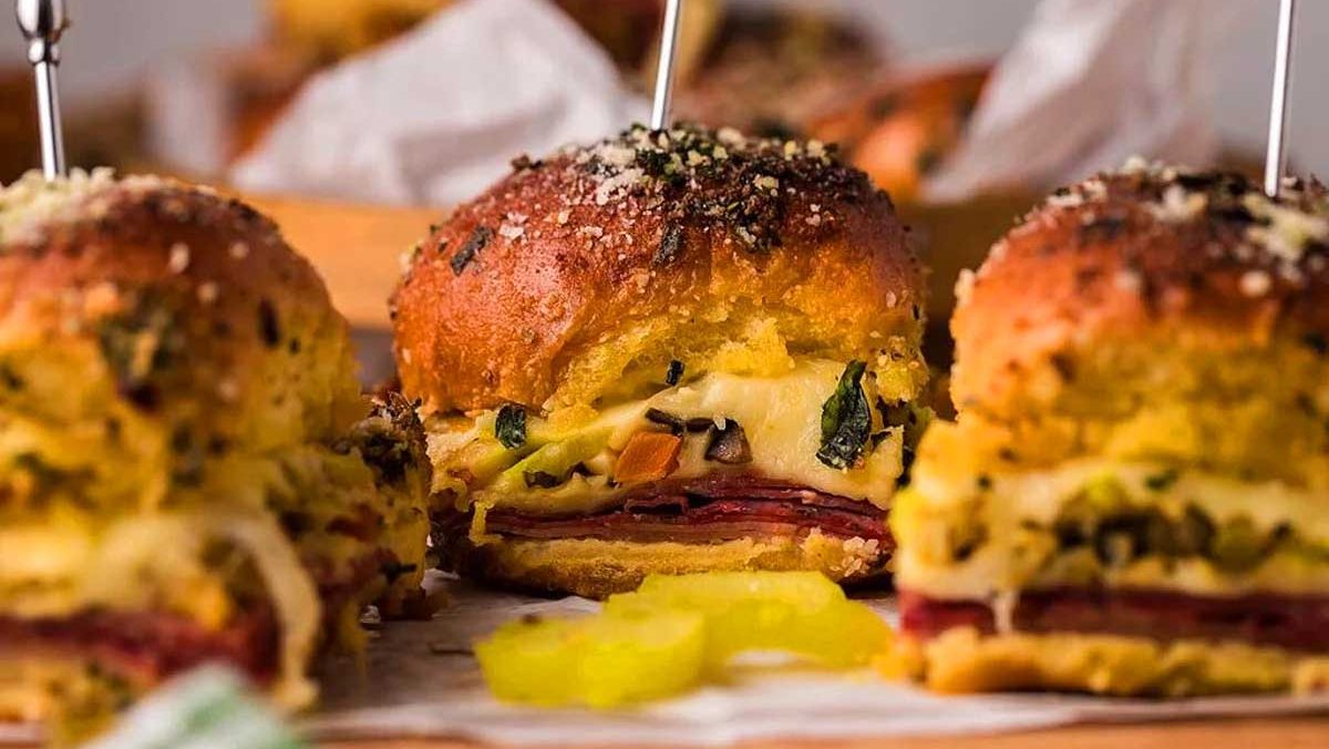 Pub-style ham and cheese sliders on a wooden cutting board.