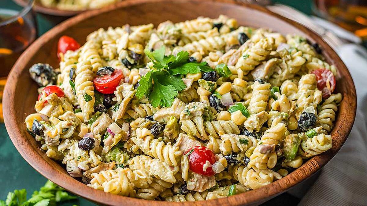A pasta salad with black olives, tomatoes, and parsley.