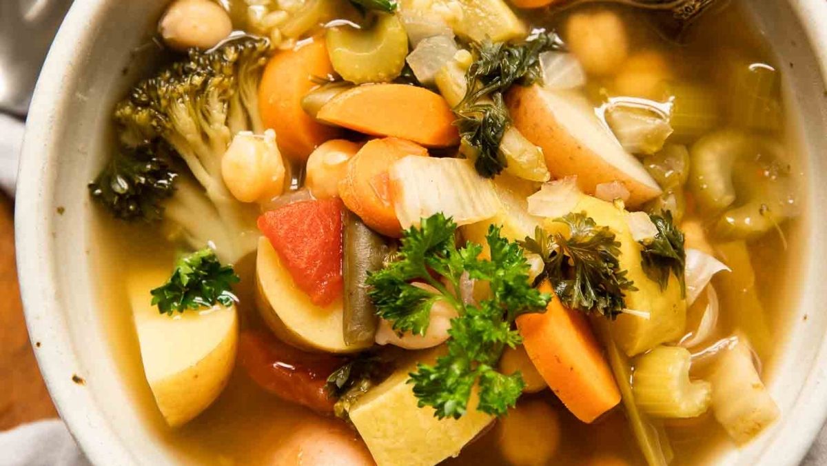 Explore delectable vegetable soup recipes with this satisfying bowl of soup accompanied by a handy spoon.