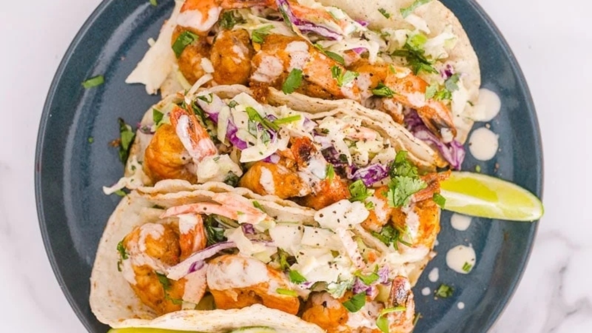 Dinner plate with shrimp tacos and lime wedges.