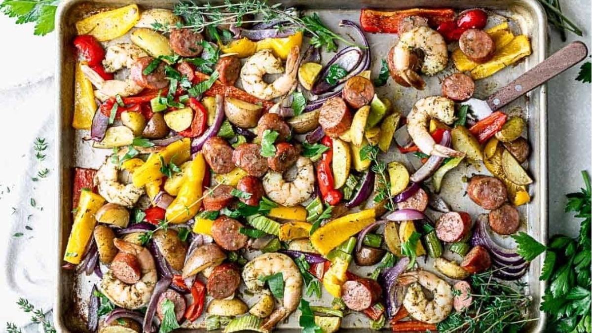 A dinner spread featuring a baking sheet with 23 shrimp and assorted vegetables.