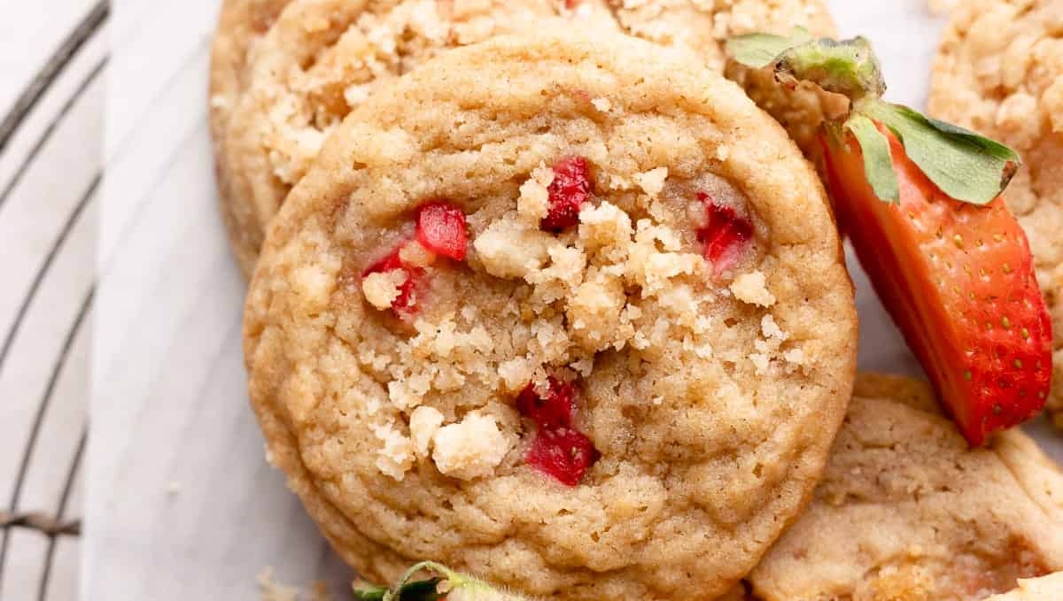 Close-up of strawberry crumble cookies on a wire cooling rack, garnished with fresh strawberry slices.