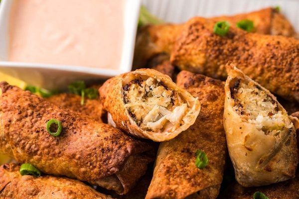 Chicken spring rolls with dipping sauce on a plate.
