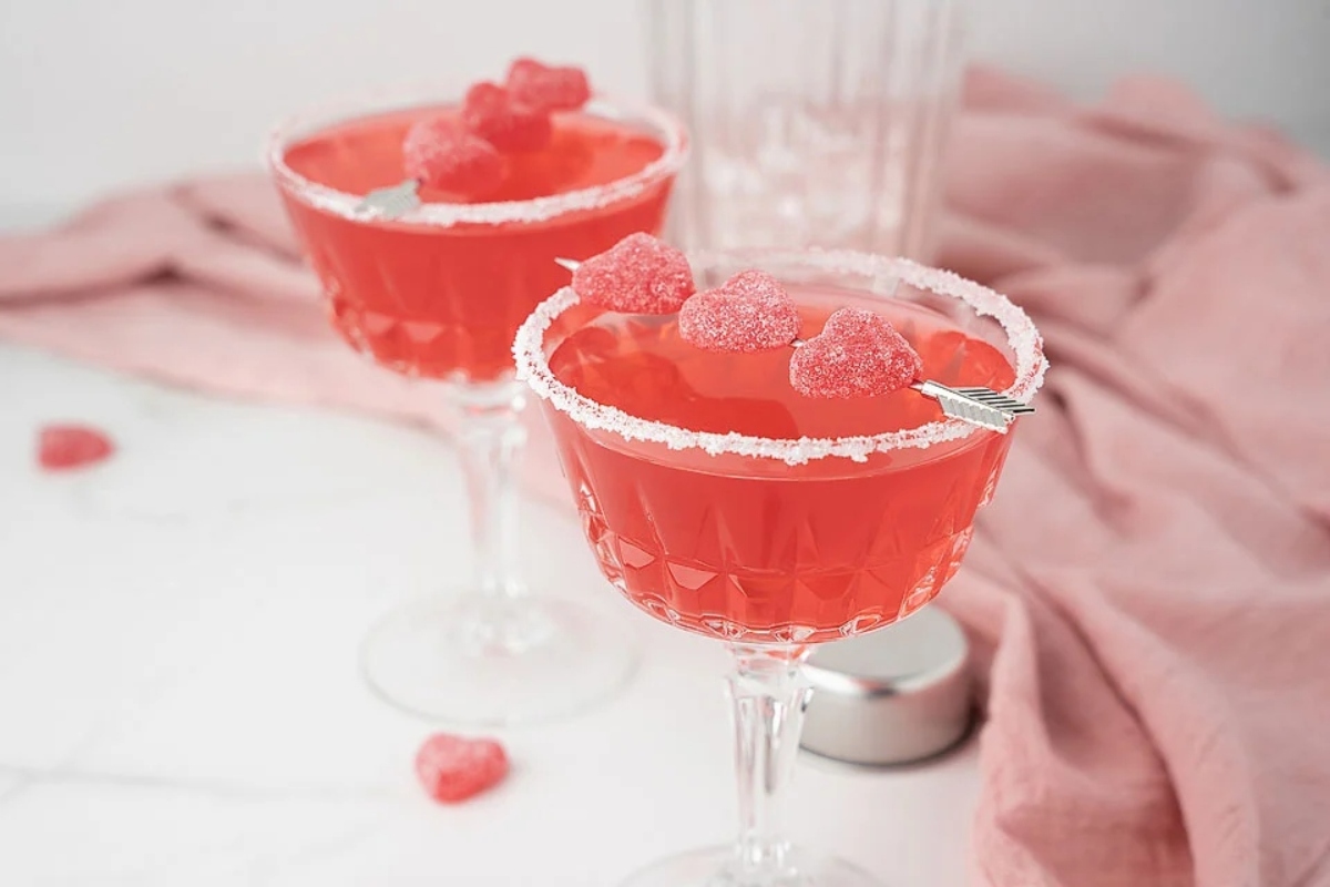 Two pink cocktails with raspberries on top, perfect for Valentine's Day.